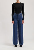 A stylish outfit featuring high-waisted, wide-leg blue jeans paired with a fitted, long-sleeve black top.
