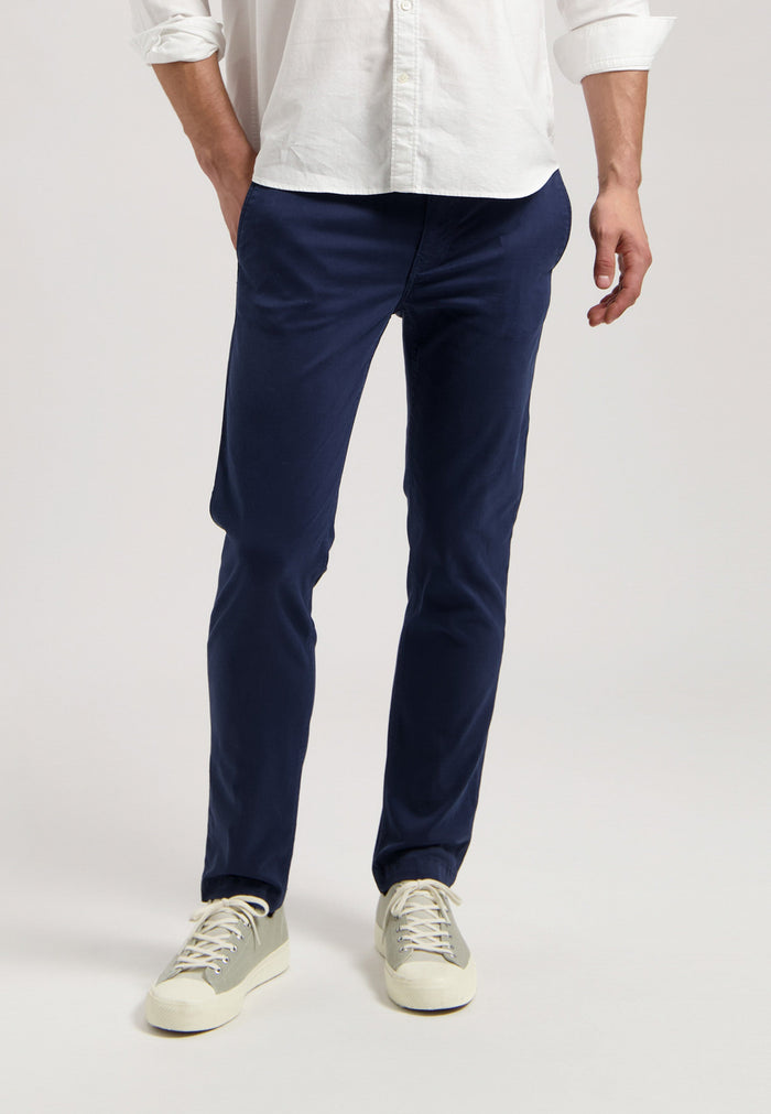 Sustainable MUD Jeans in dark gray denim, crafted ethically, paired with black sneakers and a black T-shirt.