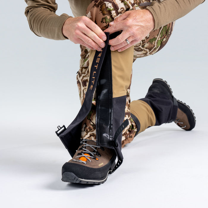 Close up of model wearing First Lite boot gaiters, adjusting the hook and loop closure