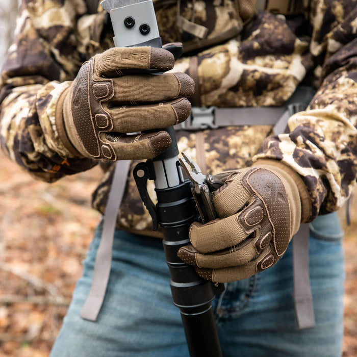 Two-toned brown and tan tactical gloves with textured knuckle and finger accents, worn by a person holding a pole and multi-tool.