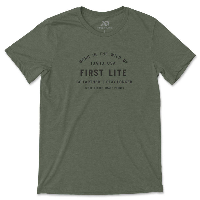 Olive green t-shirt featuring black text graphic "Born in the Wild of Idaho, USA First Lite Go Farther | Stay Longer Since Before Smart Phones".