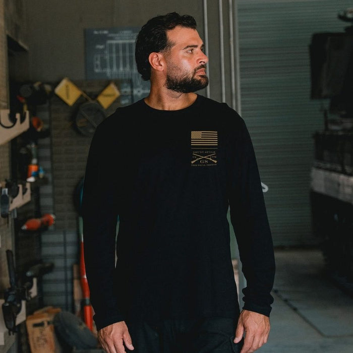 Man wearing a black long-sleeve shirt with a logo in a workshop setting