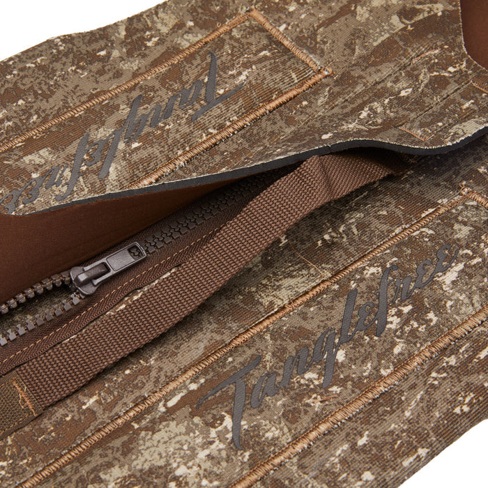 Close-up of brown and tan camouflage gear fabric with a dark brown plastic zipper, a woven strap, and "Tanglefree" branding.