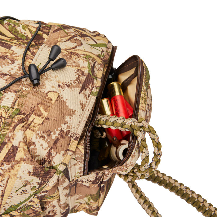 First Lite camouflage utility pouch with an open zippered compartment revealing red shotgun shells and a green and tan braided paracord lanyard.