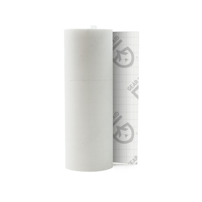White roll of transparent repair tape, partially unrolled to show its clear grid-patterned backing with 'GEAR AID' logo.