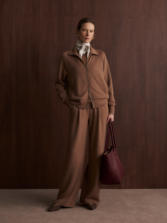 Golden Bronze Marl|Model standing facing forward with hands in pockets, wearing the Tyde Zip Through Sweat in golden bronze marl, crafted from DoubleSoft® fabric, featuring a two-way zip, knitted collar, and vertical welt pockets.