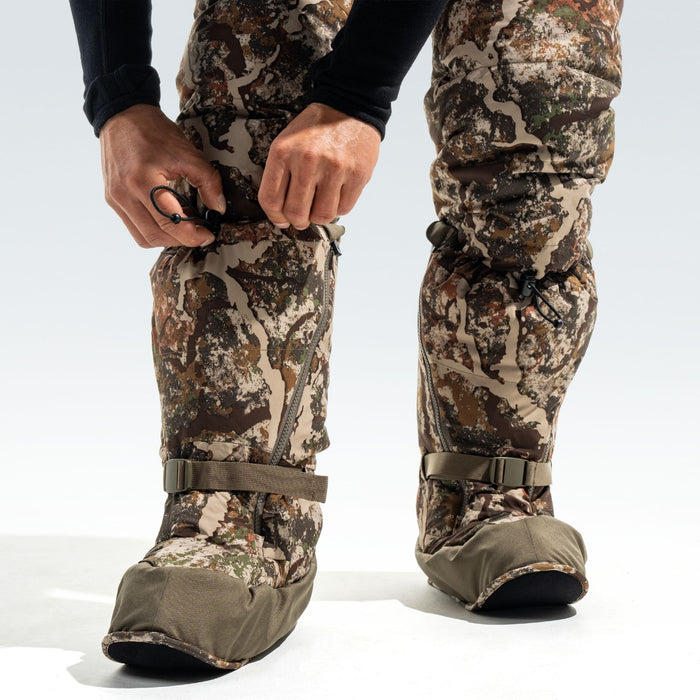 Man adjusting the fit of his camo overboots.