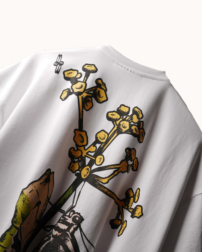Close-up of a white crewneck sweatshirt featuring a graphic print of yellow flowers and green leaves on the front.