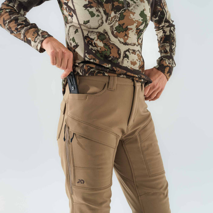 Tan outdoor pants with a knife in the front pocket, zippered thigh pockets, and articulated knee stitching.