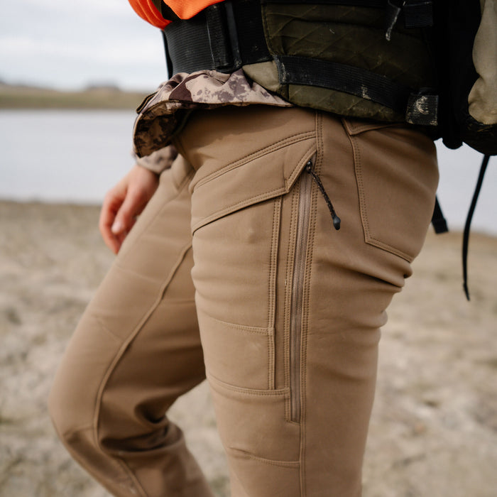 Tan outdoor pants with a zippered thigh pocket and an upper flap pocket.