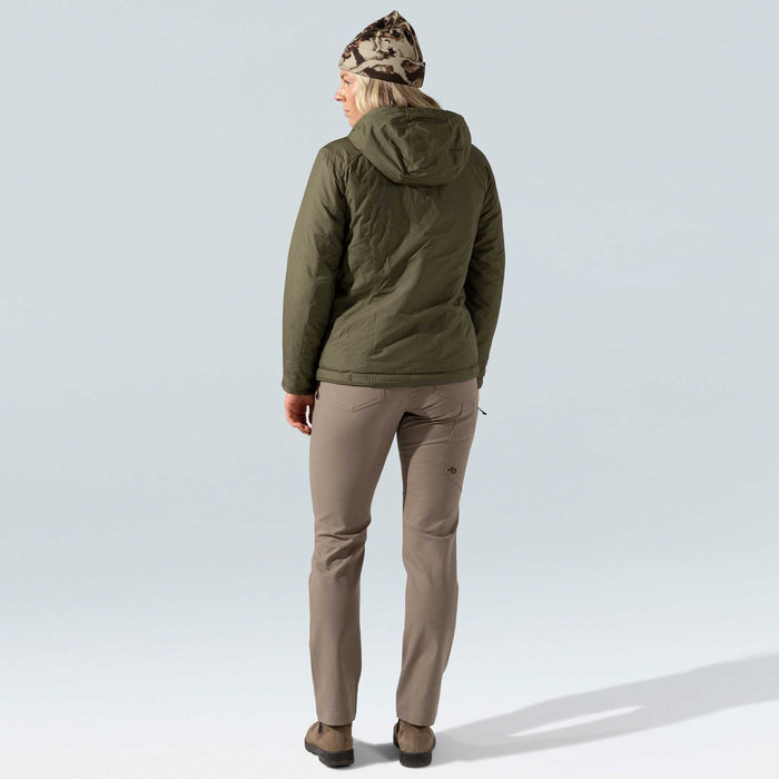 A woman from behind wears an olive green quilted hooded jacket, taupe outdoor pants with a thigh pocket logo, and a camouflage beanie.