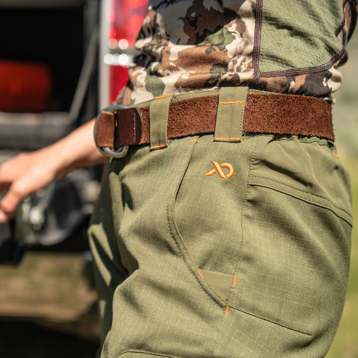Olive green pants with orange stitching and an orange logo, worn with a brown leather belt.