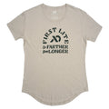 A light tan short-sleeve t-shirt with a crew neck, curved hem, and a dark green "FIRST LITE Go FARTHER Stay LONGER" graphic on the front.